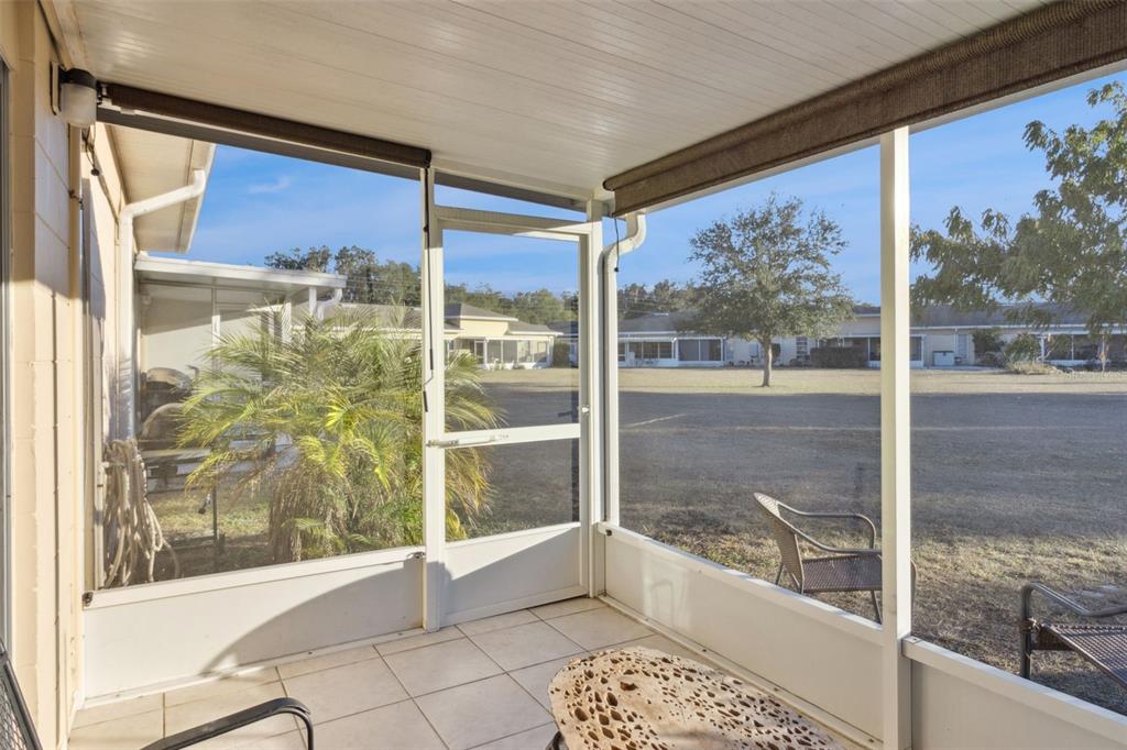 A screened-in porch with tiled flooring overlooks a grassy yard and neighboring houses — 3037 CLUB CIR, LAKESHORE, FL