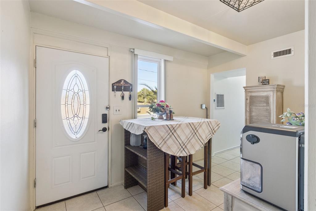 An entryway features a white front door, a small dining table, and tiled flooring — 3037 CLUB CIR, LAKESHORE, FL