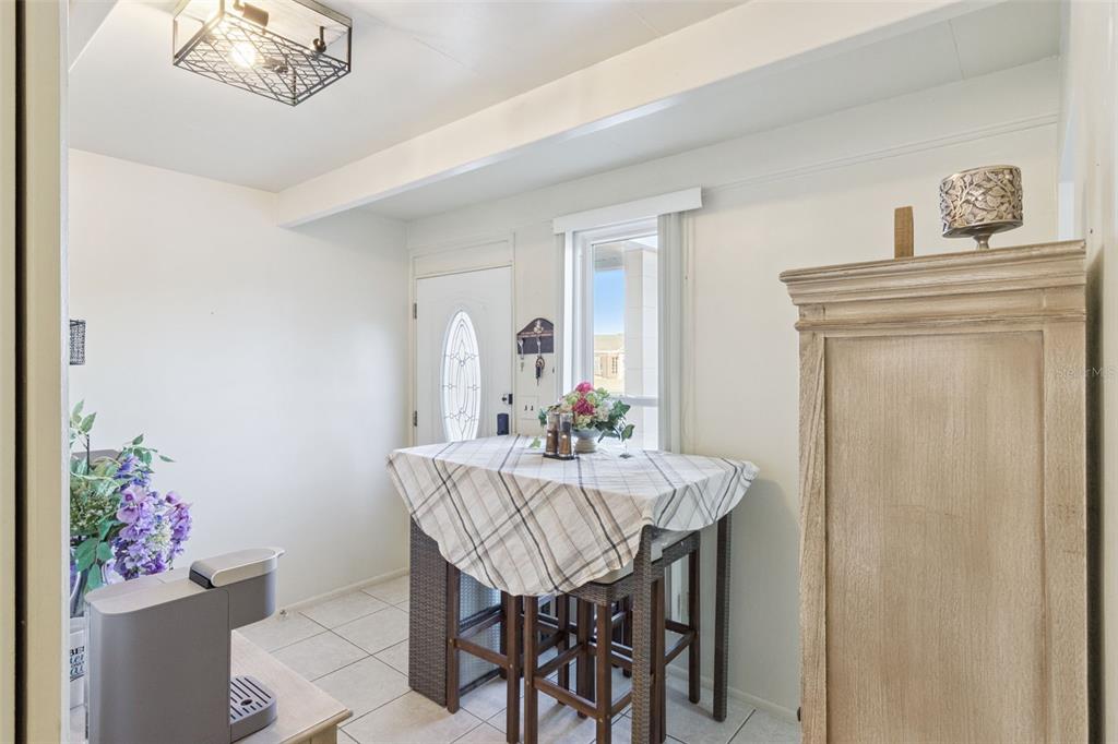 A small dining area features a high-top table, tiled floors, and a white entry door — 3037 CLUB CIR, LAKESHORE, FL