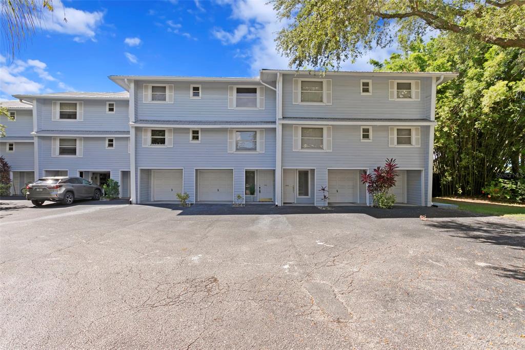 A multi-story light blue townhouse building with multiple garage bays and a paved parking lot — 4863 W FLAMINGO ROAD UNIT 2, TAMPA, FL