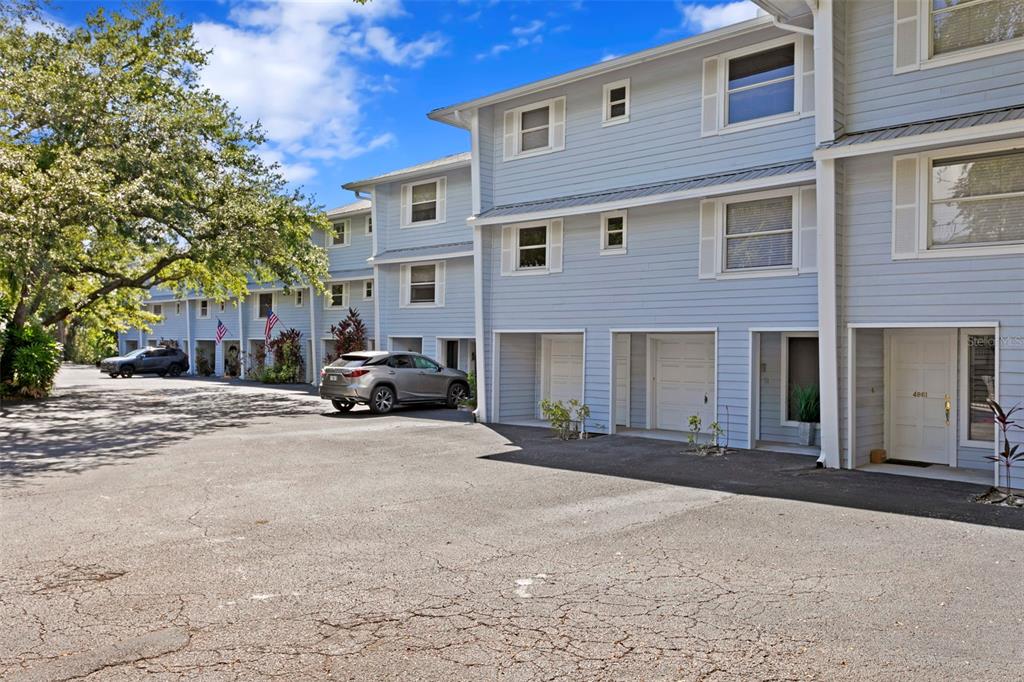 A row of light blue multi-story townhomes with covered ground-level parking and paved driveway — 4863 W FLAMINGO ROAD UNIT 2, TAMPA, FL