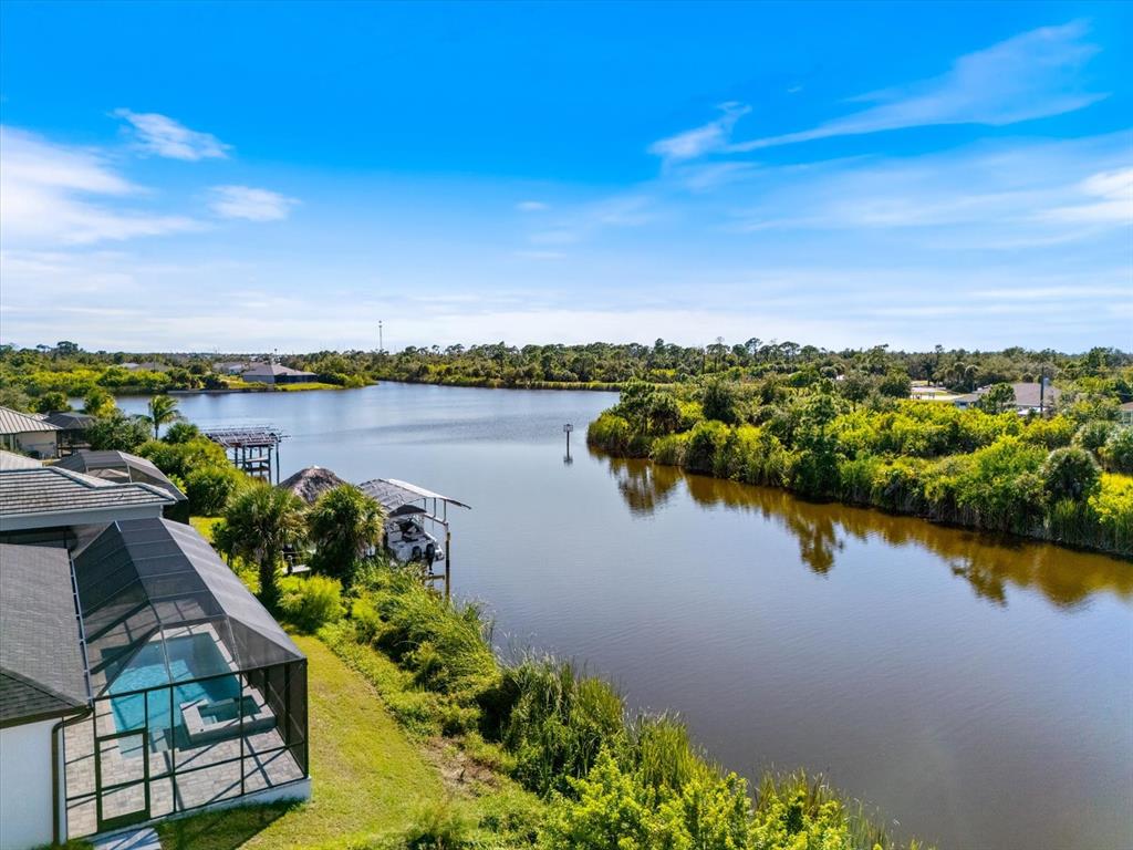 An aerial view of a house with a screened pool overlooking a lake and trees — 10123 BOYLSTON STREET, PORT CHARLOTTE, FL