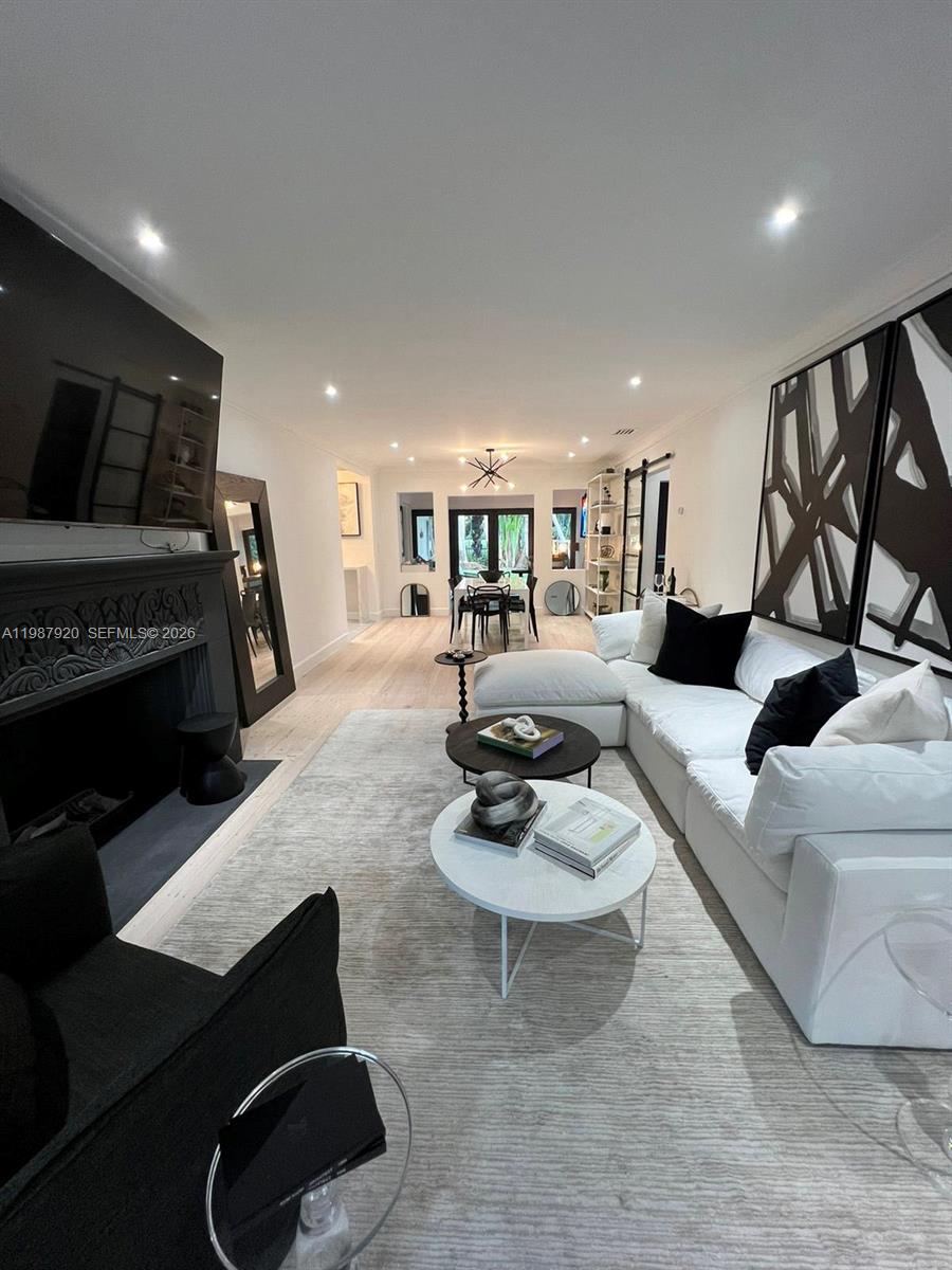 A modern living room features a white sectional sofa, a fireplace, and light wood flooring — 5173 Alton Rd, Miami Beach FL 33140, MIAMI BEACH, FL