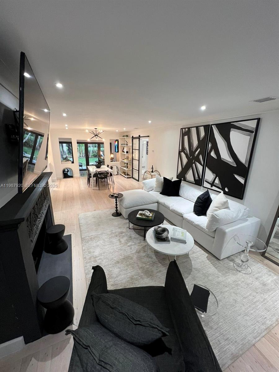 A modern living room features a white sectional sofa, black fireplace, and abstract wall art — 5173 Alton Rd, Miami Beach FL 33140, MIAMI BEACH, FL