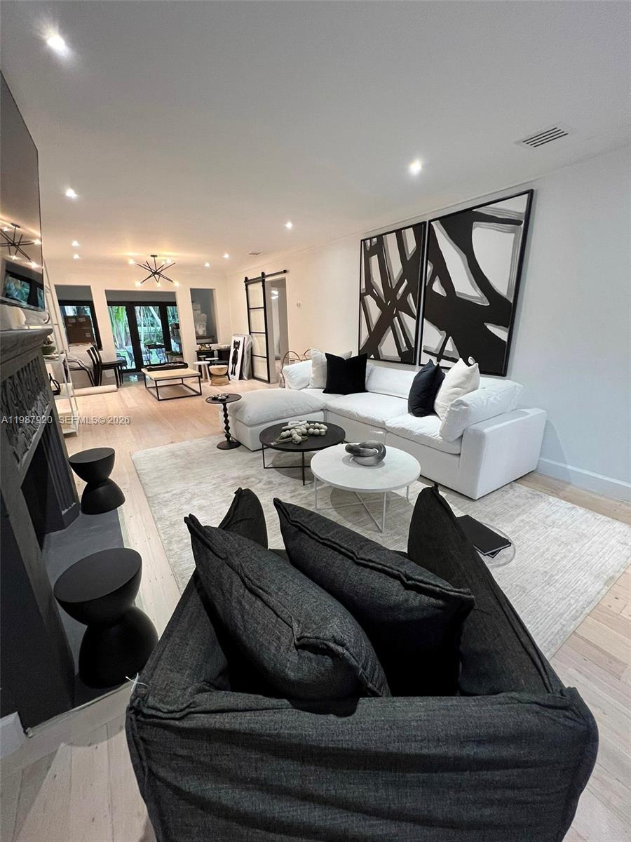 A modern living room features a white sectional sofa, black accent pillows, and abstract wall art — 5173 Alton Rd, Miami Beach FL 33140, MIAMI BEACH, FL