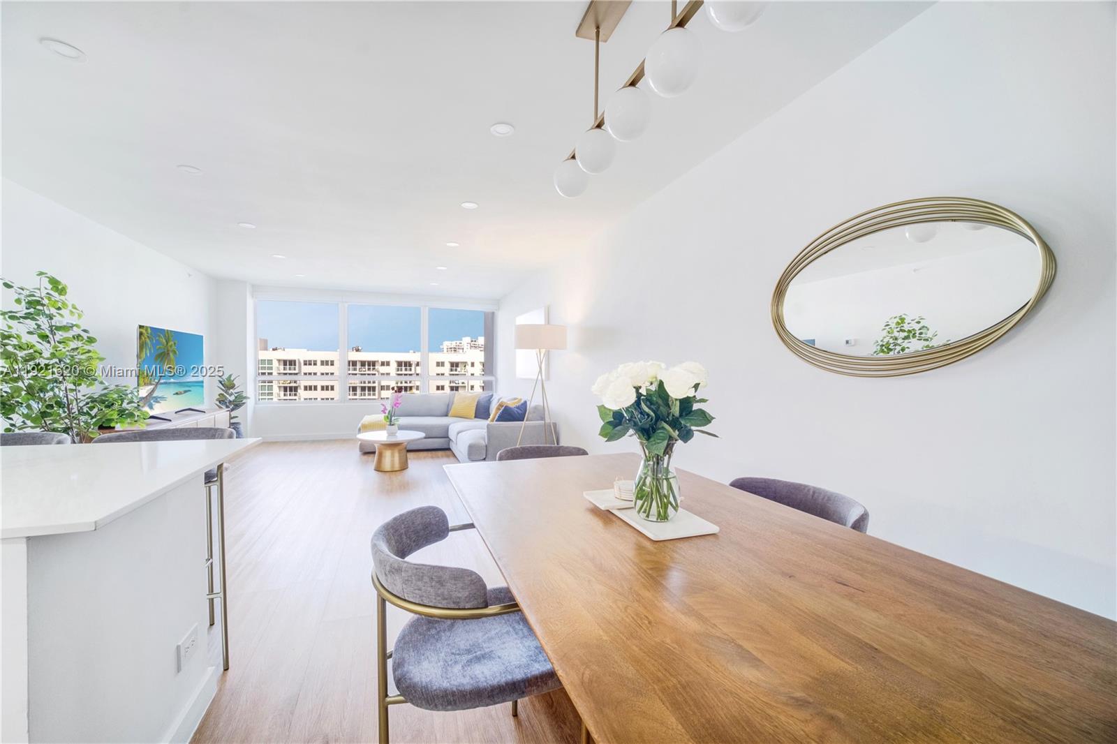 A bright, open-concept living and dining area features wood flooring, modern furniture, and large windows — 1500 Bay Rd # 1558S, Miami Beach FL 33139, MIAMI BEACH, FL