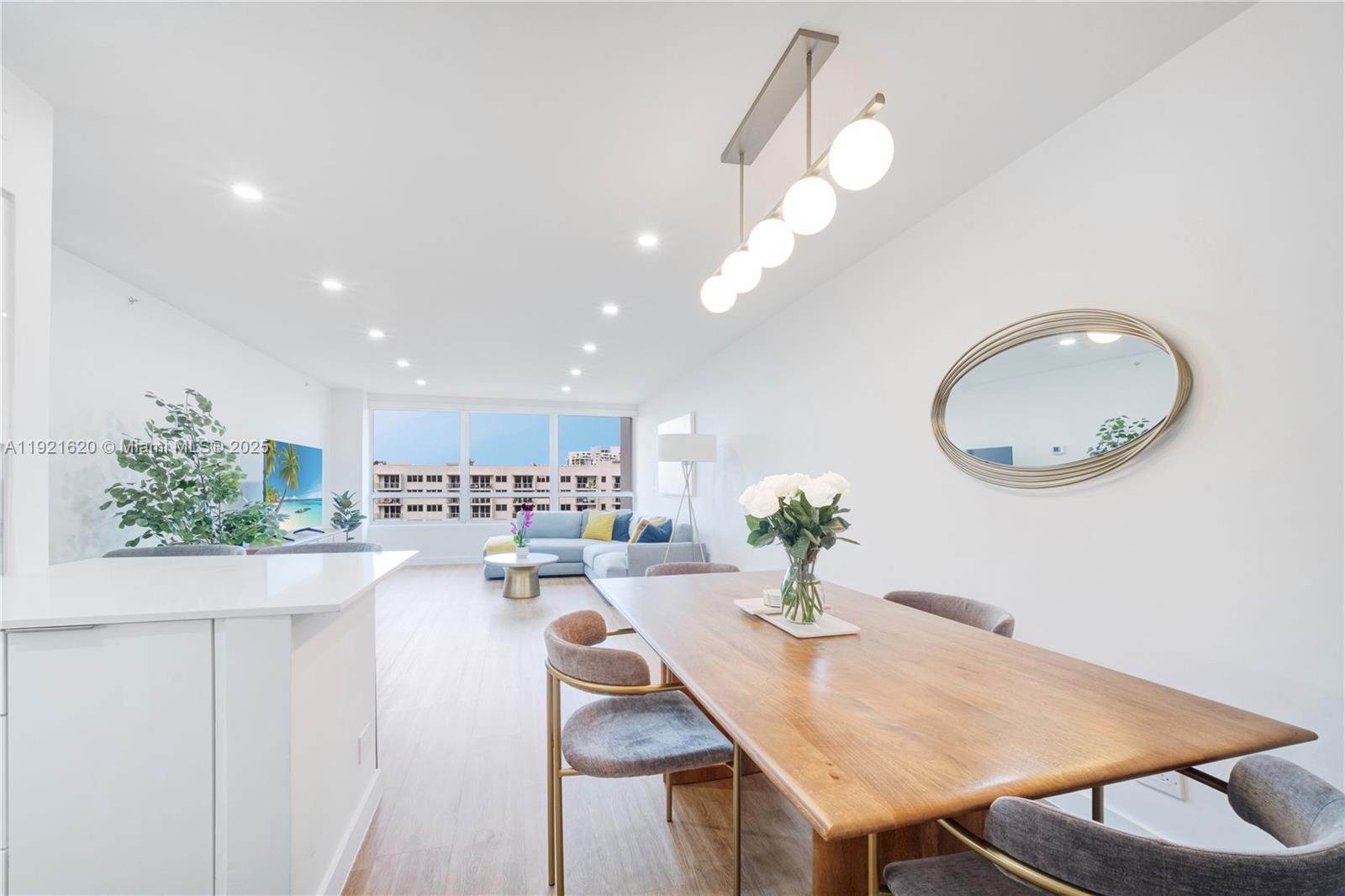 A modern dining and living area features a wooden table, pendant lighting, and large windows — 1500 Bay Rd # 1558S, Miami Beach FL 33139, MIAMI BEACH, FL