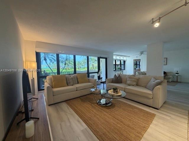 A living room features two beige sofas, a jute rug, and floor-to-ceiling windows — LAUDERDALE BY THE SEA, FL