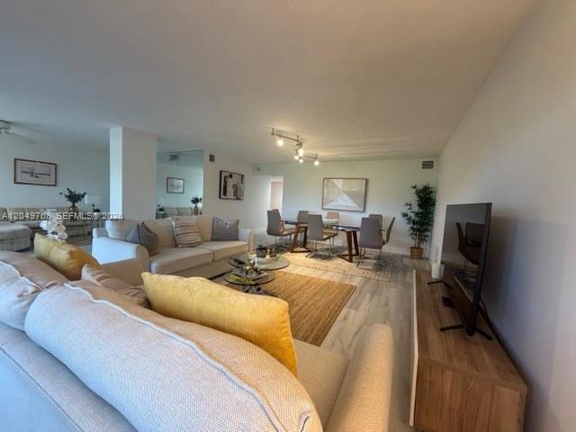 A living room features a beige sofa, a dining area, and a television on a stand — LAUDERDALE BY THE SEA, FL