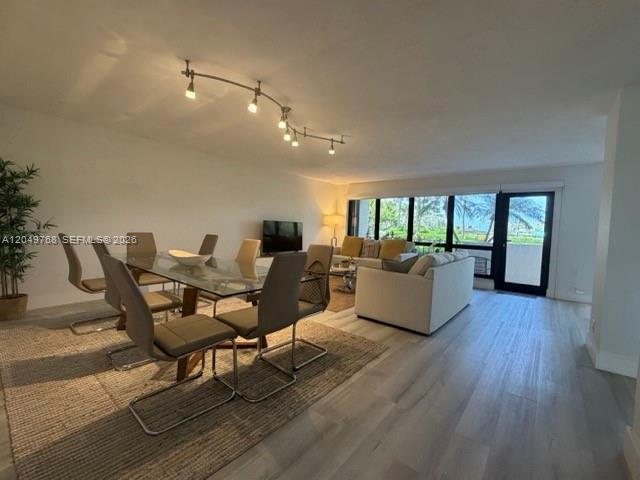 A dining area with a glass table and chairs sits beside a living room area — LAUDERDALE BY THE SEA, FL