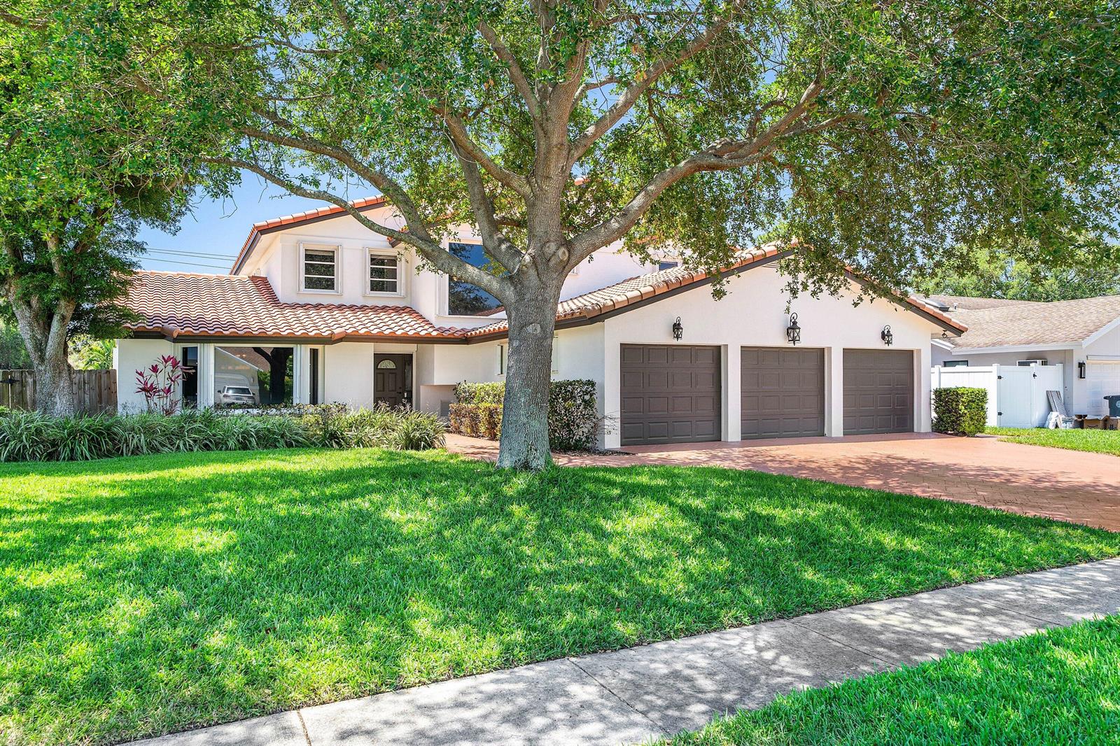 A two-story house with a tile roof, three garage doors, and a large front tree — 1560 SW 17th Street, Boca Raton FL 33486, BOCA RATON, FL
