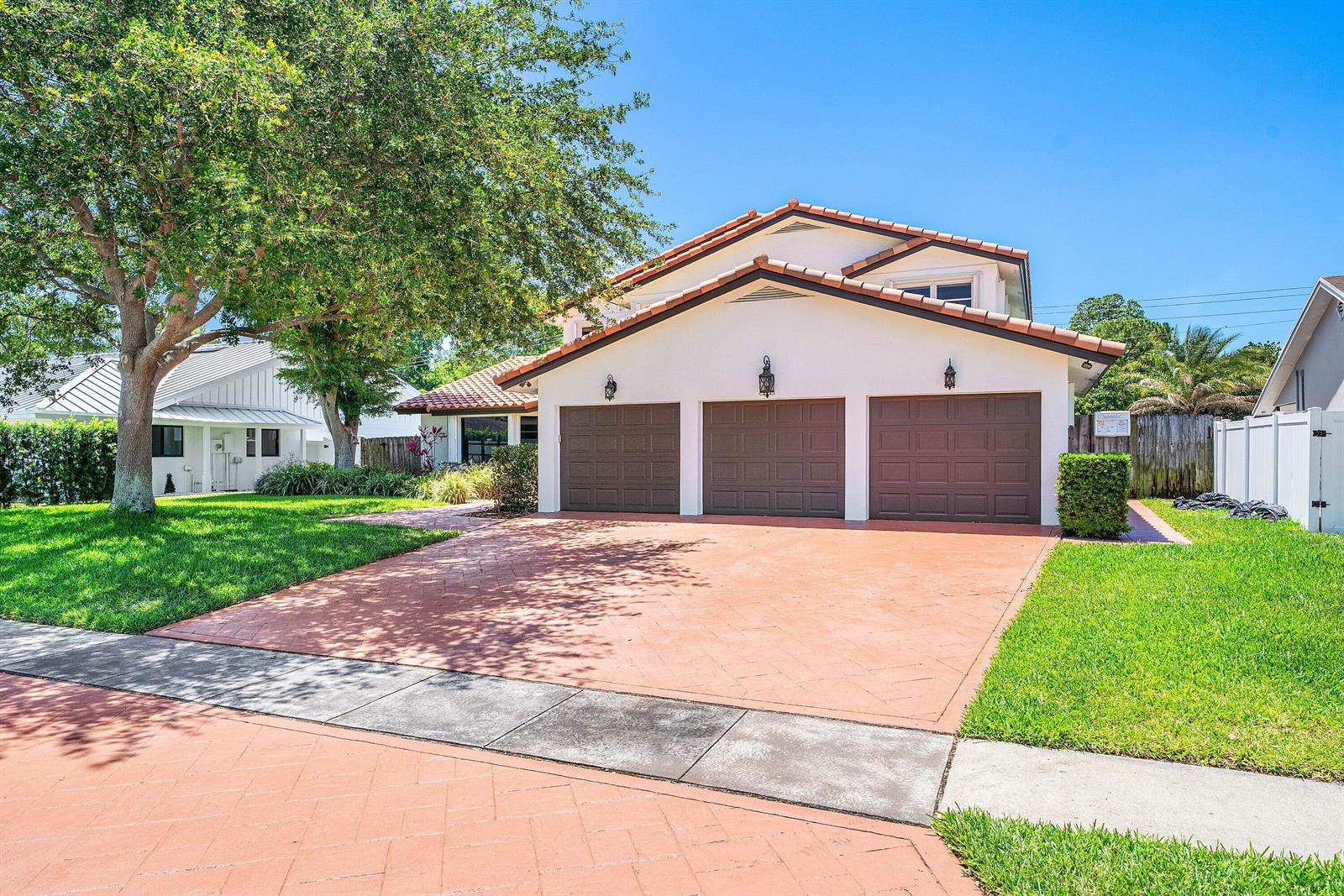 A three-car garage house with a red-tiled roof and a paved driveway under a tree — 1560 SW 17th Street, Boca Raton FL 33486, BOCA RATON, FL