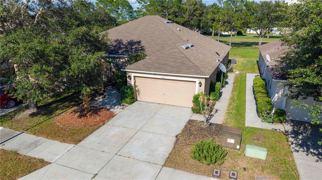 An aerial view of a suburban house with a tan garage and brown shingled roof — 9139 SOUTHERN CHARM CIRCLE, BROOKSVILLE, FL