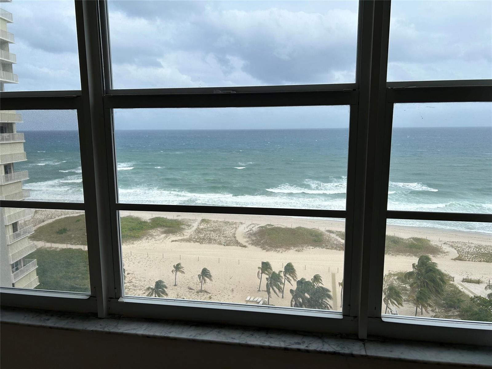 A view of the ocean and beach through a multi-pane window in a high-rise building — 750 N Ocean Boulevard # 1409, Pompano Beach FL 33062, POMPANO BEACH, FL