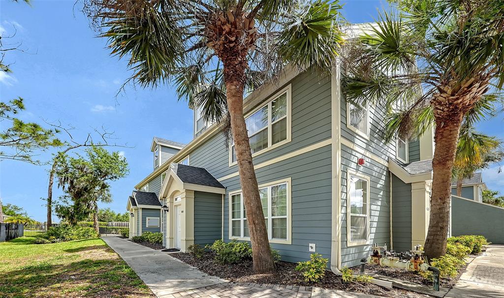A multi-story building with blue horizontal siding, white trim, and palm trees in the foreground — 5501 ROSEHILL ROAD UNIT 105, SARASOTA, FL