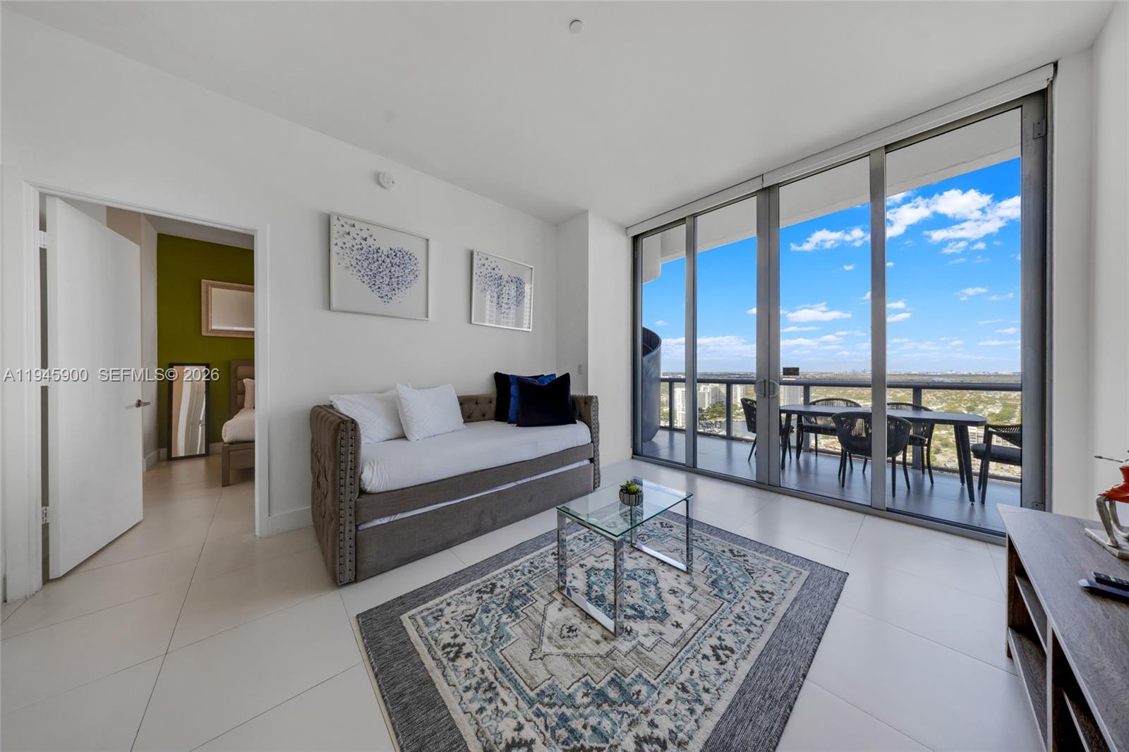 A living room features a daybed, glass coffee table, and sliding doors opening to a balcony — 2600 E Hallandale Beach Blvd # T3304, Hallandale Beach FL 33009, HALLANDALE BEACH, FL