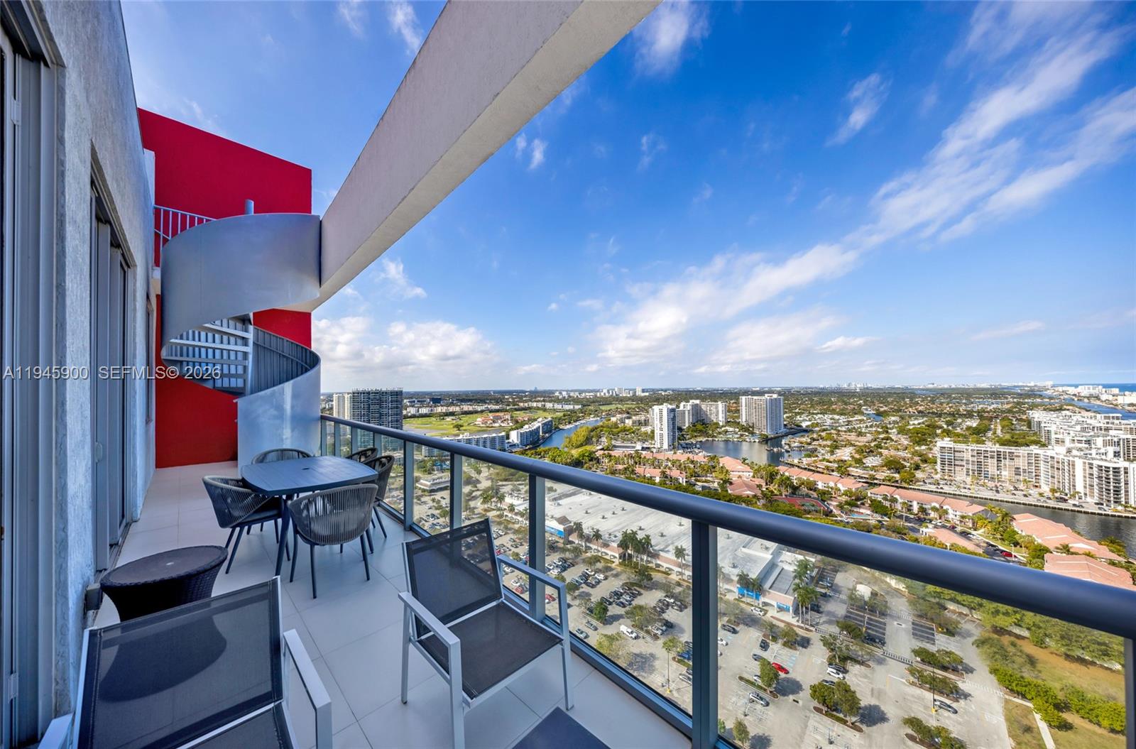 A high-rise balcony features a spiral staircase, outdoor dining furniture, and a panoramic city view — 2600 E Hallandale Beach Blvd # T3304, Hallandale Beach FL 33009, HALLANDALE BEACH, FL