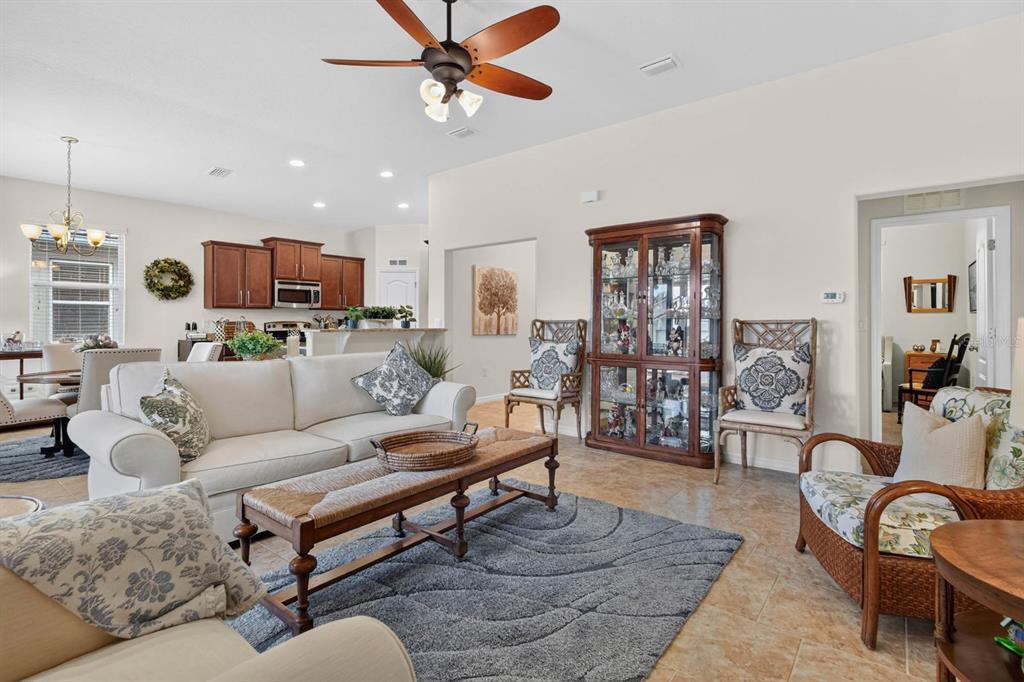 A living room with a beige sofa, a wooden coffee table, and a glass display cabinet — 3451 PONETA AVENUE, NEW SMYRNA BEACH, FL