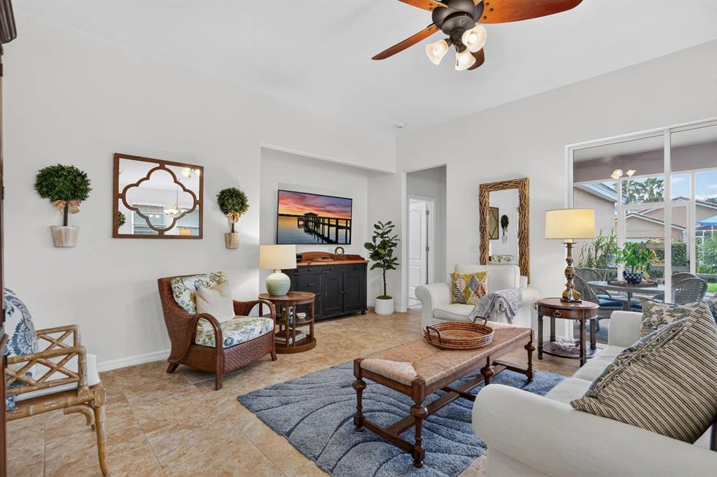 A living room features tile flooring, a ceiling fan, a television, and patio access — 3451 PONETA AVENUE, NEW SMYRNA BEACH, FL