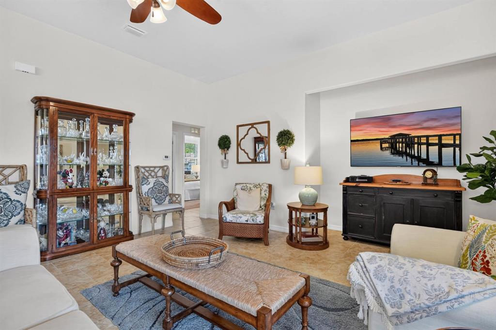 A living room features a wooden display cabinet, a television, and a woven coffee table — 3451 PONETA AVENUE, NEW SMYRNA BEACH, FL