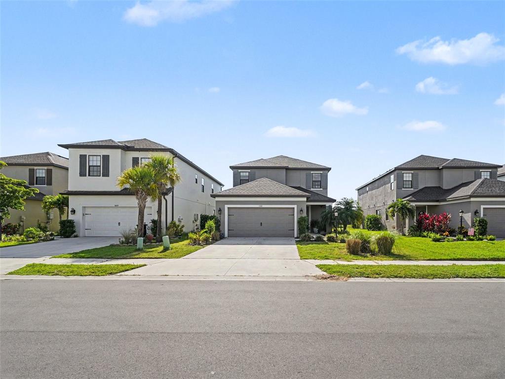 Three two-story suburban houses with attached garages stand side-by-side along a residential street — 5461 SUMMIT GLEN, BRADENTON, FL