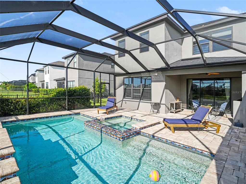 A screened-in patio features a swimming pool, a raised spa, and two lounge chairs — 5461 SUMMIT GLEN, BRADENTON, FL