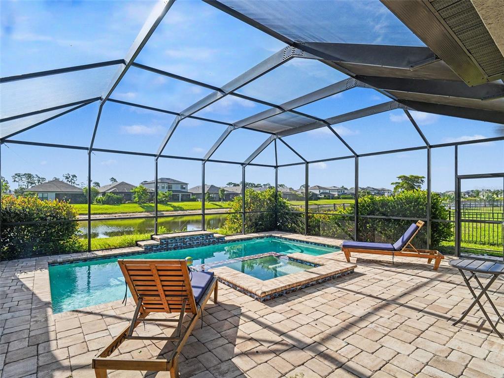 A screened-in patio features a swimming pool, a hot tub, and two lounge chairs — 5461 SUMMIT GLEN, BRADENTON, FL