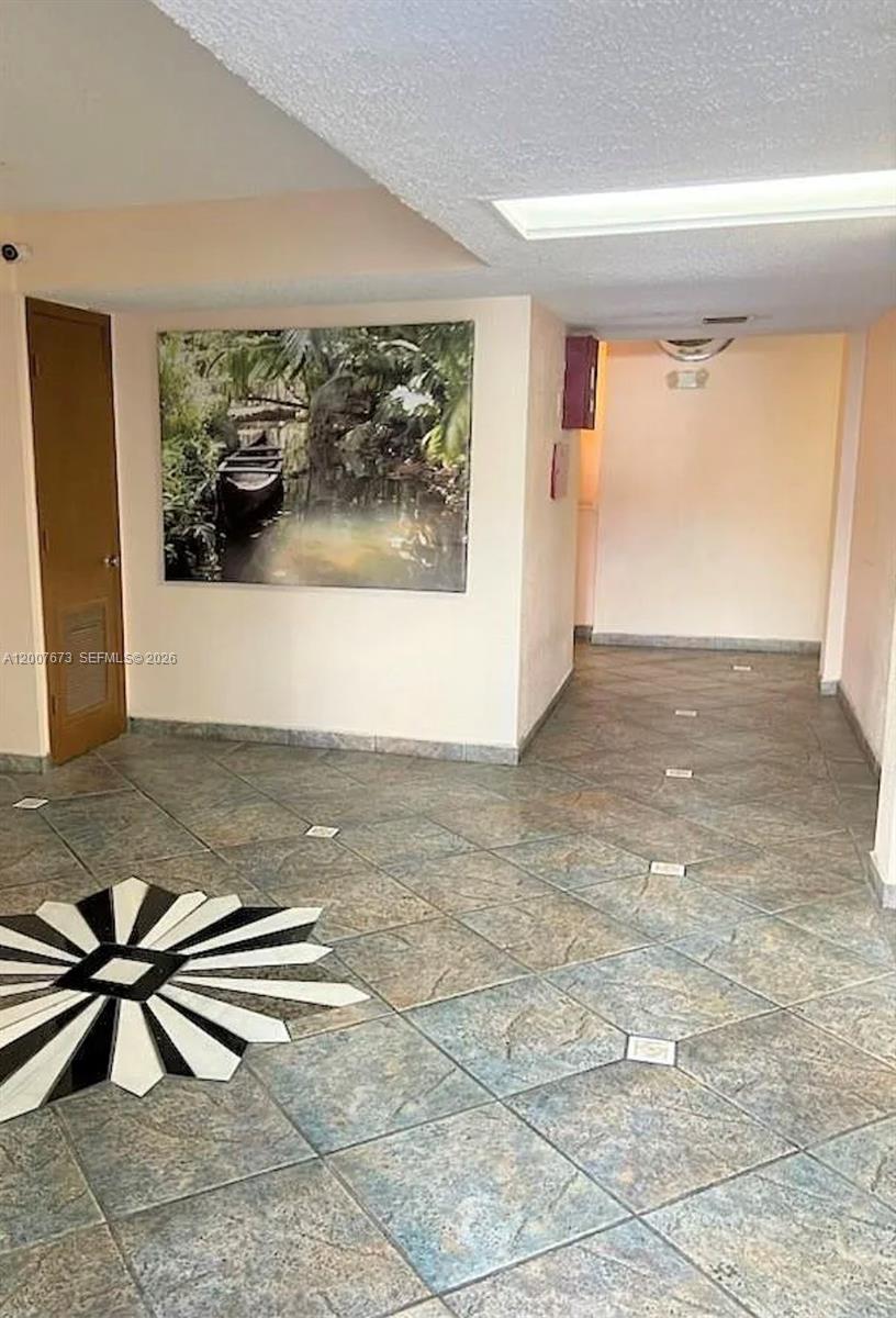 A tiled hallway features a large landscape wall art piece and a decorative floor inlay — 110 S Shore Dr # 5B, Miami Beach FL 33141, MIAMI BEACH, FL