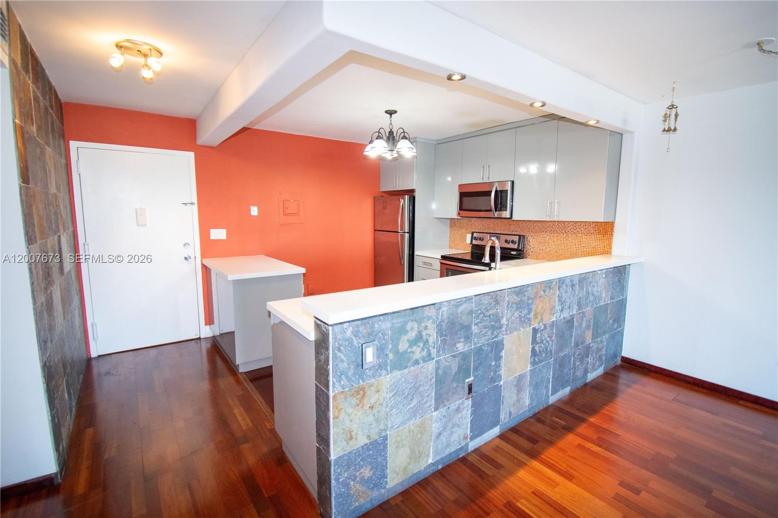 A kitchen with a slate-tiled breakfast bar, orange accent wall, and light gray cabinetry — 110 S Shore Dr # 5B, Miami Beach FL 33141, MIAMI BEACH, FL