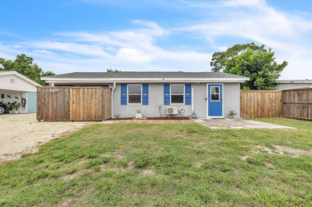 A gray single-story house with blue shutters, a blue front door, and a wooden privacy fence — 1144 PINE STREET, ENGLEWOOD, FL