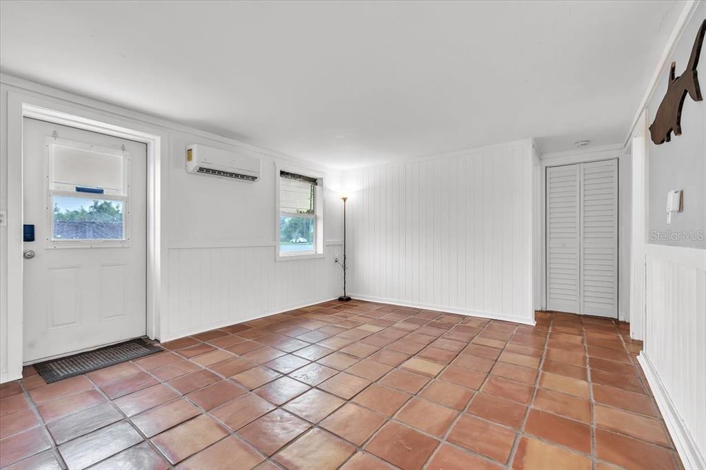 A living room features terracotta tile floors, a fireplace, a mounted television, and white walls — 1144 PINE STREET, ENGLEWOOD, FL