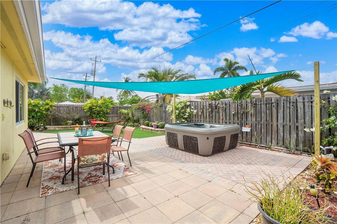 A backyard patio features a dining set, a hot tub, and a turquoise shade sail — 161 SE 5th Court, Pompano Beach FL 33060, POMPANO BEACH, FL