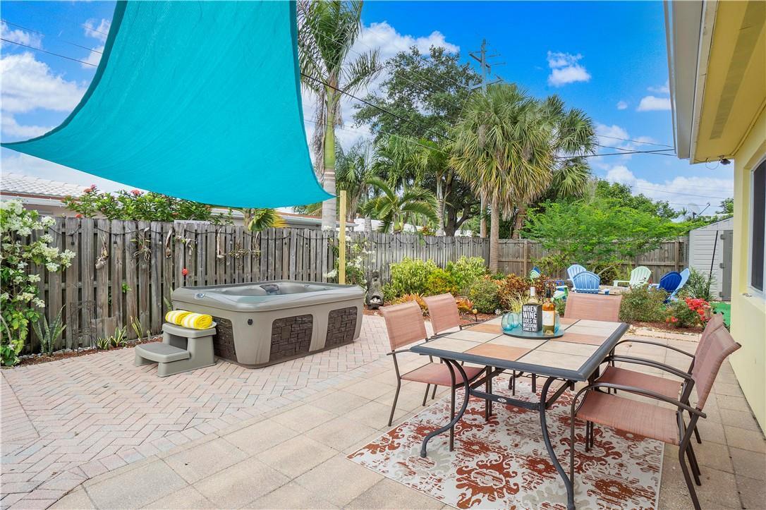 A backyard patio features a hot tub, a dining set, and a blue shade sail — 161 SE 5th Court, Pompano Beach FL 33060, POMPANO BEACH, FL