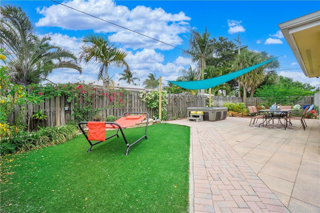 A backyard patio features a paver floor, artificial turf, a hot tub, and a shade sail — 161 SE 5th Court, Pompano Beach FL 33060, POMPANO BEACH, FL