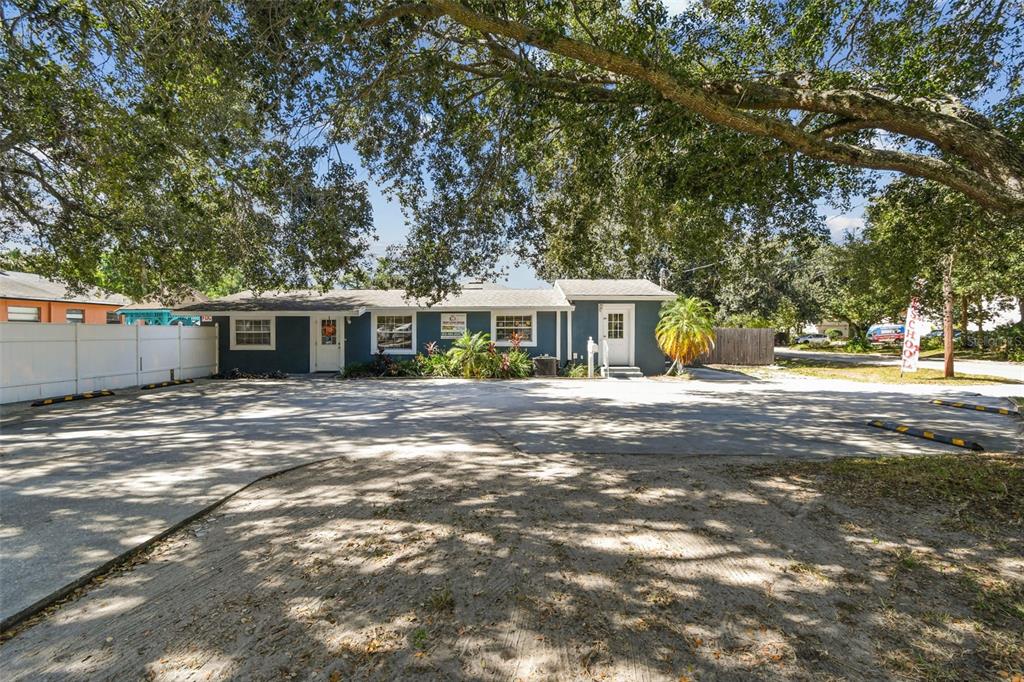 A single-story blue building with a large parking lot and mature trees in front — 9912 N MYRTLE STREET, TAMPA, FL