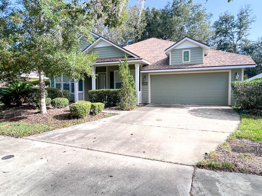A single-story house with green siding, a two-car garage, and a concrete driveway — 7509 SW 86TH WAY, GAINESVILLE, FL