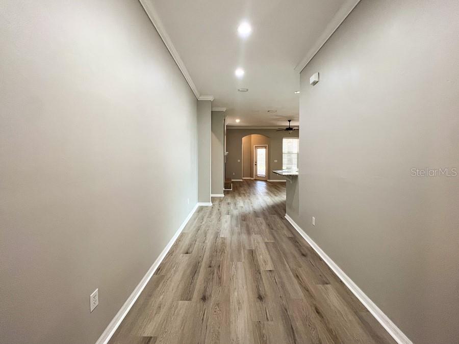 A long hallway with light gray walls and wood-look flooring leads toward an open kitchen — 7509 SW 86TH WAY, GAINESVILLE, FL