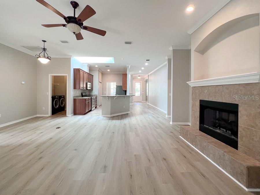 An open-concept living area features light wood-look flooring, a fireplace, and an adjacent kitchen — 7509 SW 86TH WAY, GAINESVILLE, FL