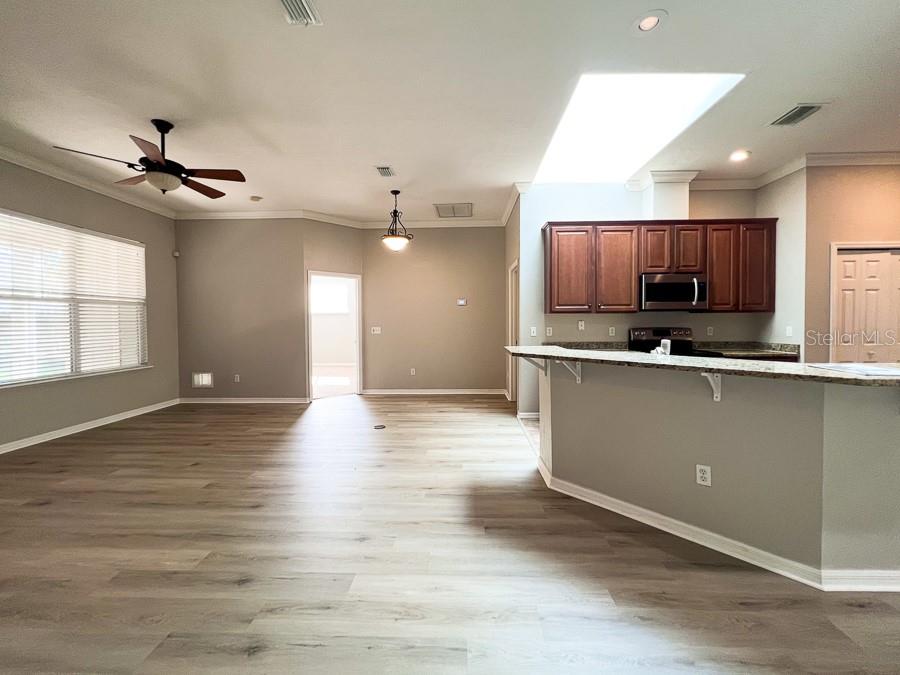 An open-concept living area features wood-look flooring, a kitchen with dark cabinets, and a skylight — 7509 SW 86TH WAY, GAINESVILLE, FL