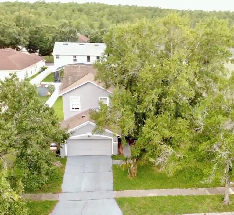 An aerial view shows a two-story gray house with a garage and a large tree — 4208 LUGANO COURT, KISSIMMEE, FL