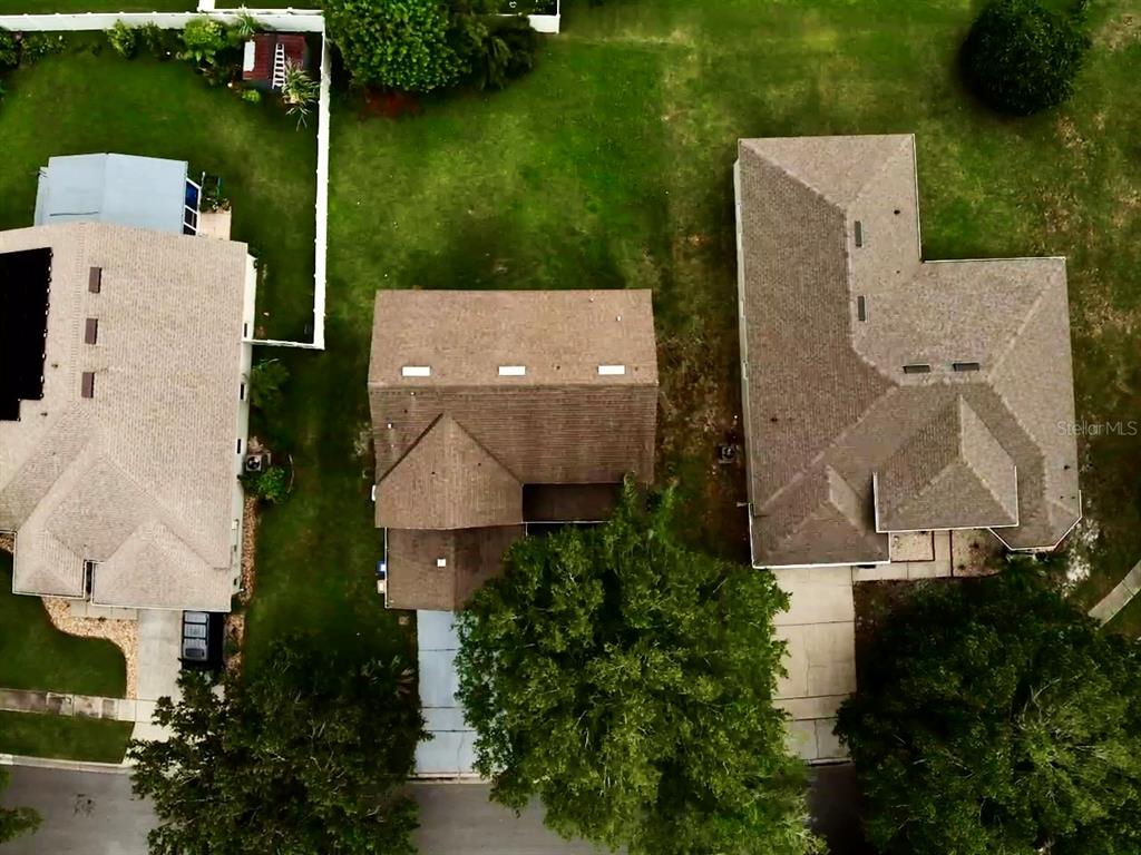 An aerial view shows three residential houses with brown roofs surrounded by green lawns — 4208 LUGANO COURT, KISSIMMEE, FL