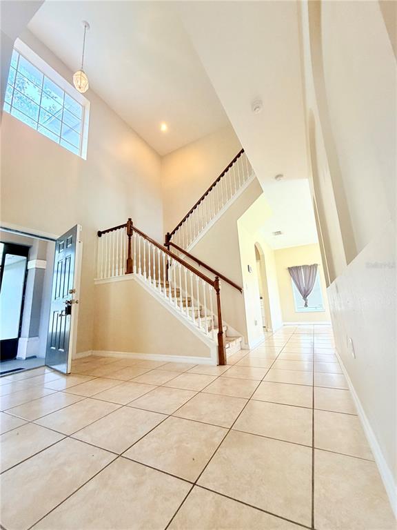 A tiled entryway features a staircase with white railings and a high ceiling — 4208 LUGANO COURT, KISSIMMEE, FL
