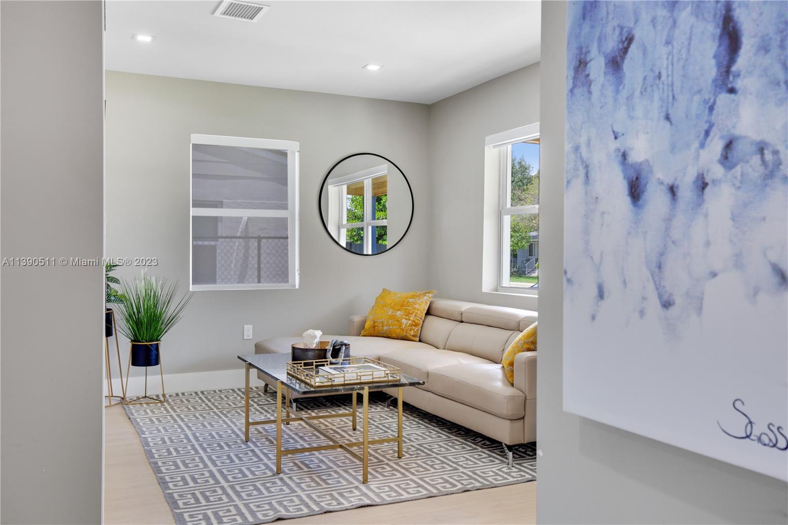 A living room features a beige sectional sofa, a geometric rug, and a round mirror — 6428 SW 23rd St # 6428, Miami FL 33155, MIAMI, FL