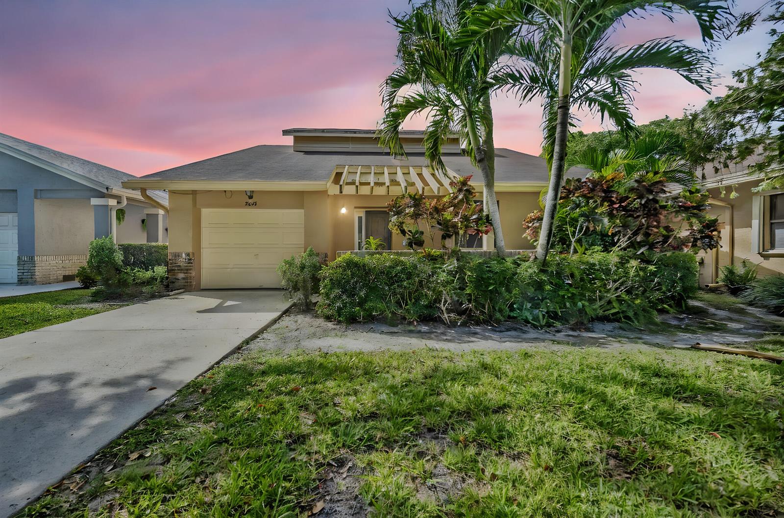A single-story house with a beige exterior, a one-car garage, and palm trees at sunset — 2643 Calliandra Terrace, Coconut Creek FL 33063, COCONUT CREEK, FL