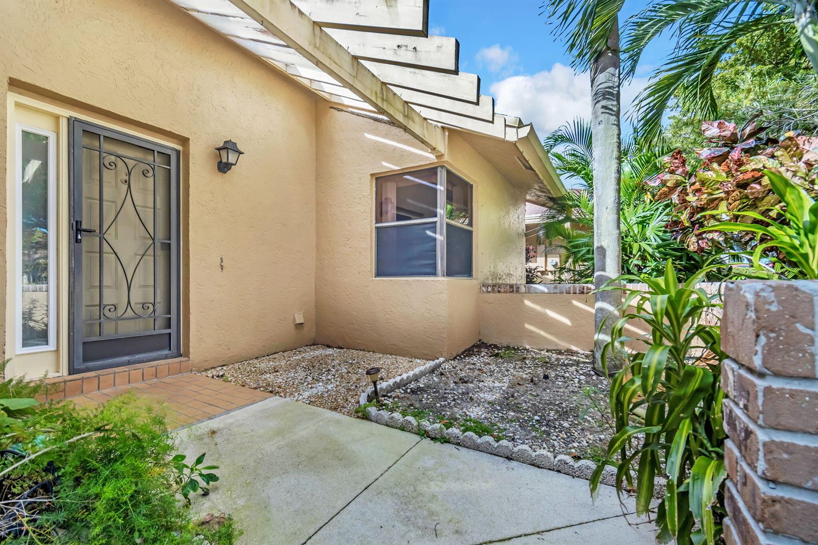 A beige stucco house exterior features a front door with a screen and a pergola — 2643 Calliandra Terrace, Coconut Creek FL 33063, COCONUT CREEK, FL