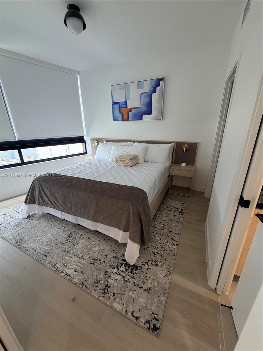 A modern bedroom features a bed with a brown throw, abstract art, and light flooring — 225 N Miami av # 907, Miami FL 33128, MIAMI, FL