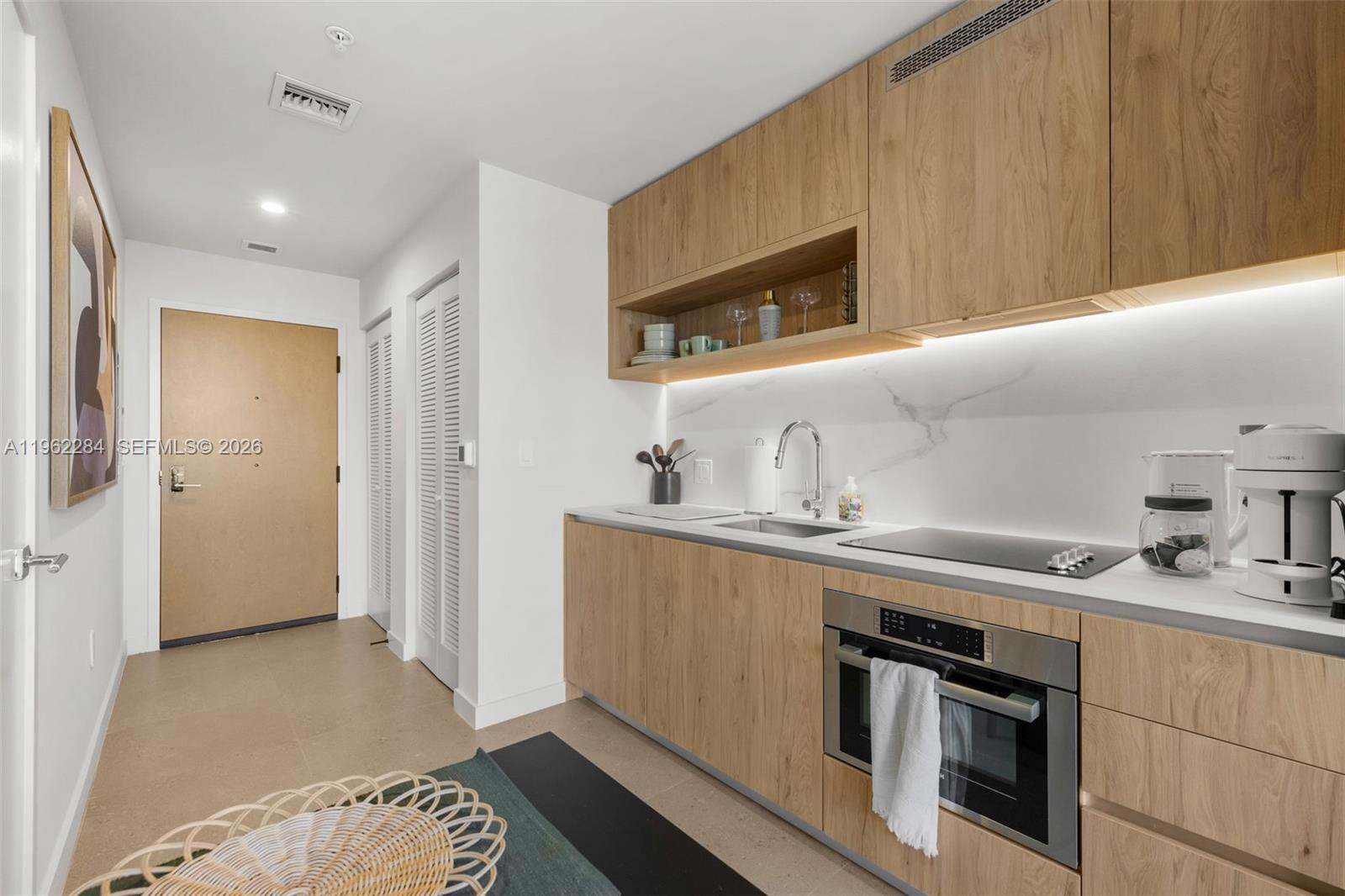 A modern kitchen features light wood cabinetry, a marble backsplash, and stainless steel appliances — 11 NE 6th St # 1615, Miami FL 33132, MIAMI, FL