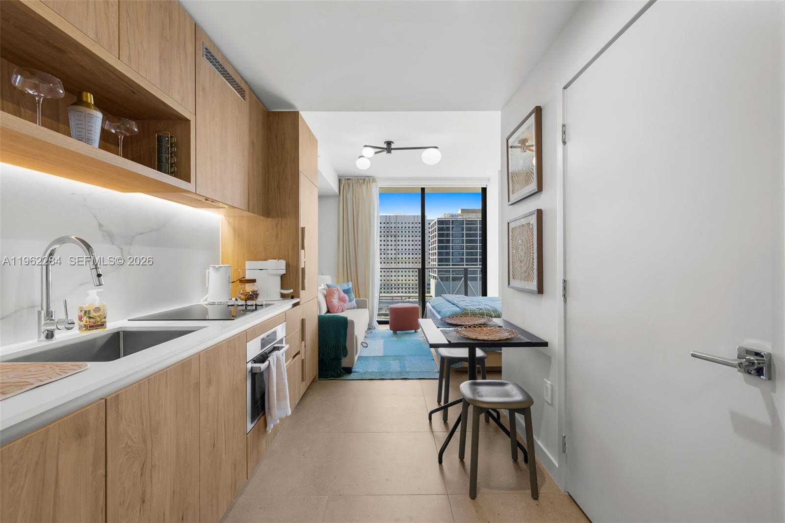 A modern studio apartment features a kitchenette with light wood cabinetry and a dining area — 11 NE 6th St # 1615, Miami FL 33132, MIAMI, FL