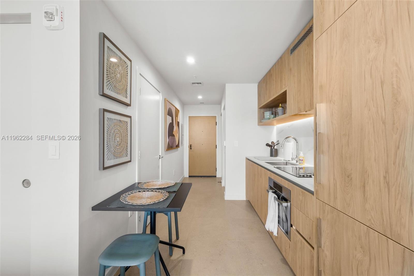 A modern kitchen features light wood cabinetry, a small dining table, and a hallway entrance — 11 NE 6th St # 1615, Miami FL 33132, MIAMI, FL