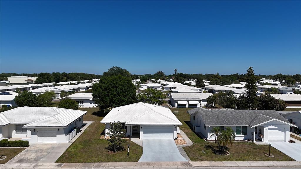 An aerial view shows three single-story suburban houses with white roofs and driveways — 709 HICKORY LANE, BRADENTON, FL